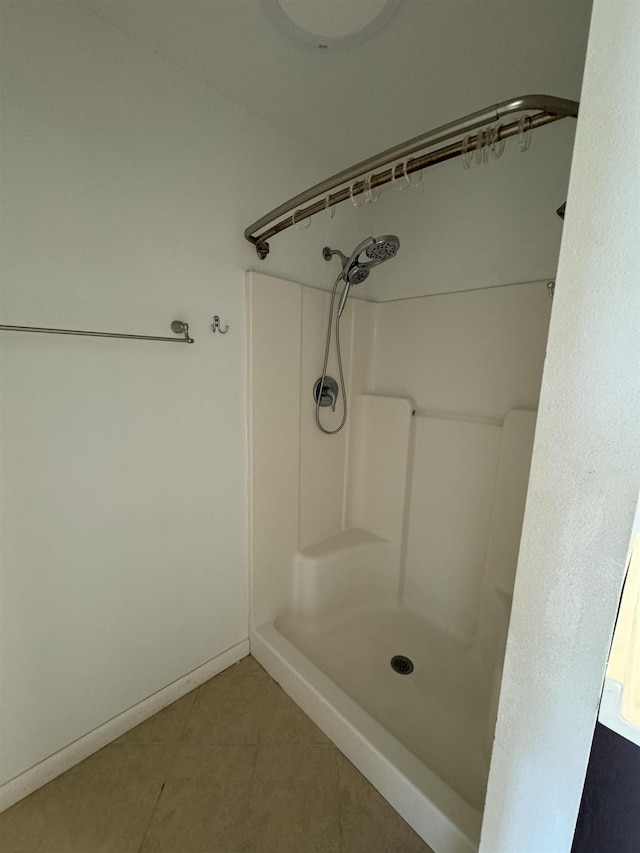 full bath featuring tile patterned flooring, baseboards, and walk in shower