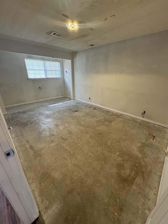 spare room featuring visible vents, concrete floors, and baseboards