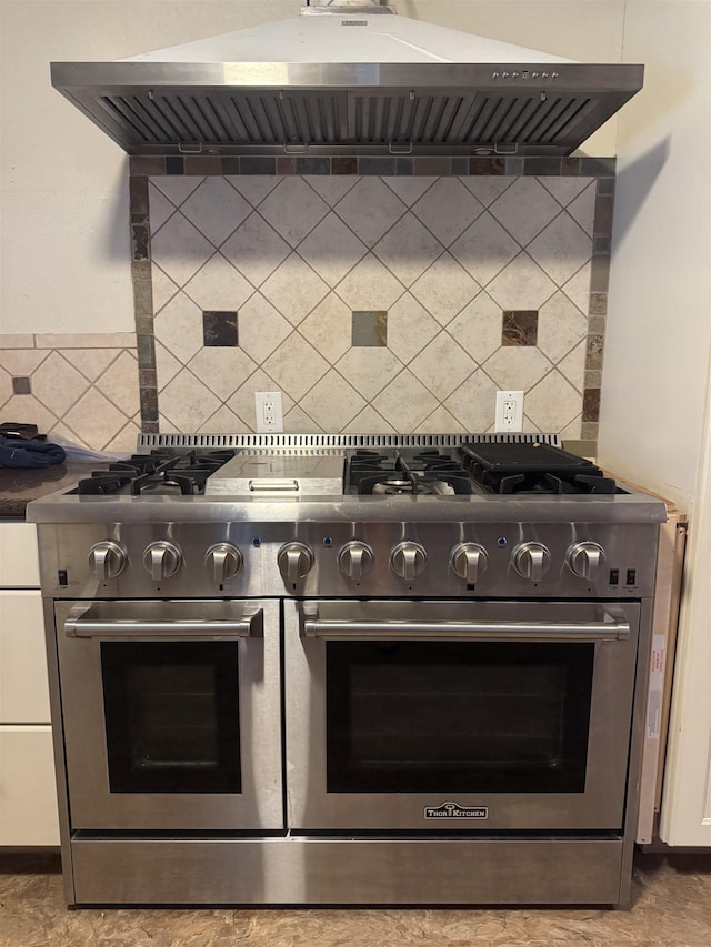room details featuring dark countertops, backsplash, extractor fan, and range with two ovens