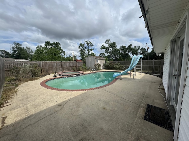 view of swimming pool featuring a storage shed, a water slide, a fenced backyard, and a patio