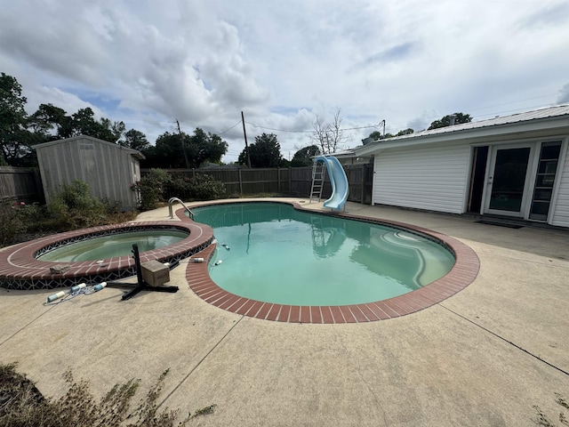 view of swimming pool with a water slide, a fenced backyard, a patio area, and a storage unit