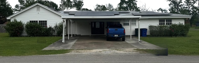 view of front facade with driveway, solar panels, a front yard, and a carport
