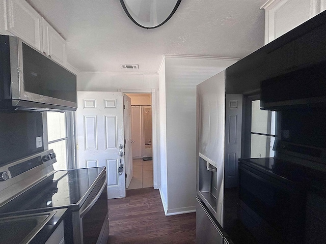 kitchen with visible vents, dark wood-type flooring, baseboards, stainless steel range with electric stovetop, and white cabinets