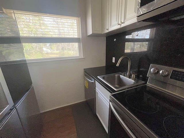 kitchen with a sink, dark countertops, appliances with stainless steel finishes, and white cabinets