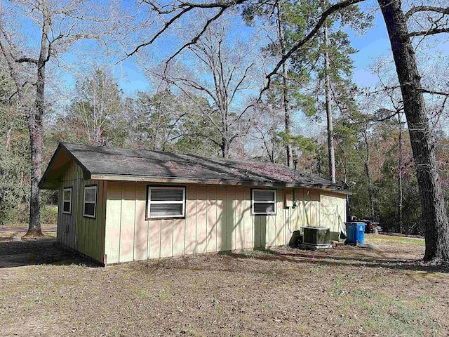 exterior space featuring central air condition unit and a forest view