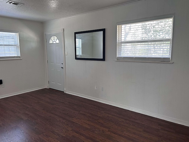 entrance foyer featuring a wealth of natural light, visible vents, a textured ceiling, and dark wood-type flooring