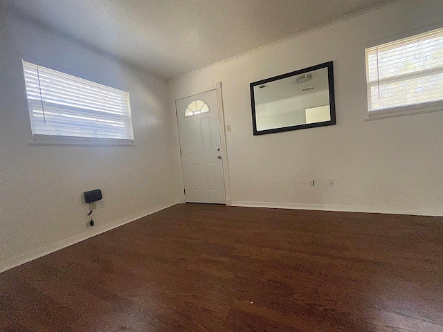 entryway with a wealth of natural light, ornamental molding, baseboards, and dark wood-style flooring