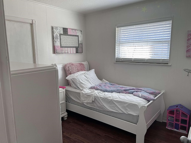 bedroom featuring a textured ceiling, wood finished floors, and ornamental molding