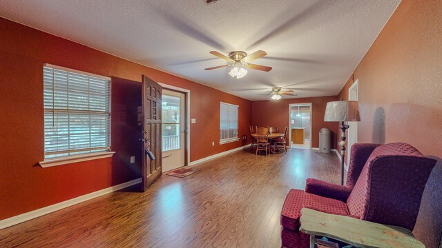 living room with ceiling fan, wood-type flooring, and a textured ceiling