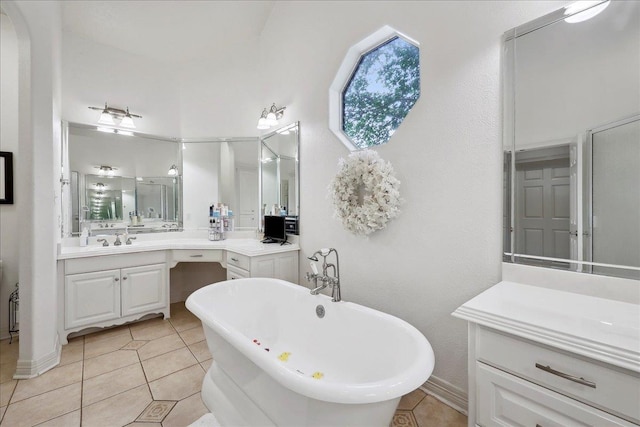 full bath featuring baseboards, tile patterned floors, a freestanding tub, and vanity