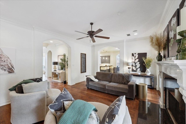 living room featuring arched walkways, a ceiling fan, visible vents, and a fireplace