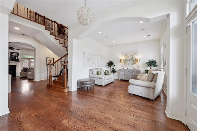 interior space featuring stairway, arched walkways, ornamental molding, and wood finished floors