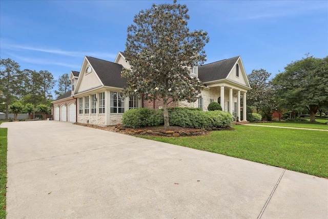 view of side of home with an attached garage, a yard, driveway, and stone siding