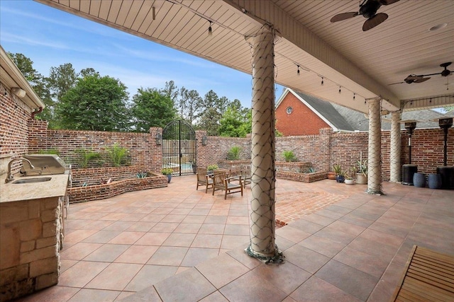view of patio featuring ceiling fan, area for grilling, a fenced backyard, a gate, and a sink