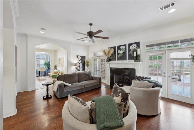 living area with visible vents, arched walkways, ceiling fan, and a healthy amount of sunlight