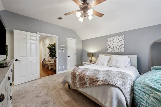 bedroom with ceiling fan, light colored carpet, visible vents, vaulted ceiling, and baseboards