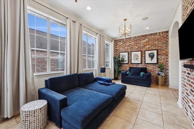 living room featuring light tile patterned floors, ornamental molding, brick wall, and a notable chandelier