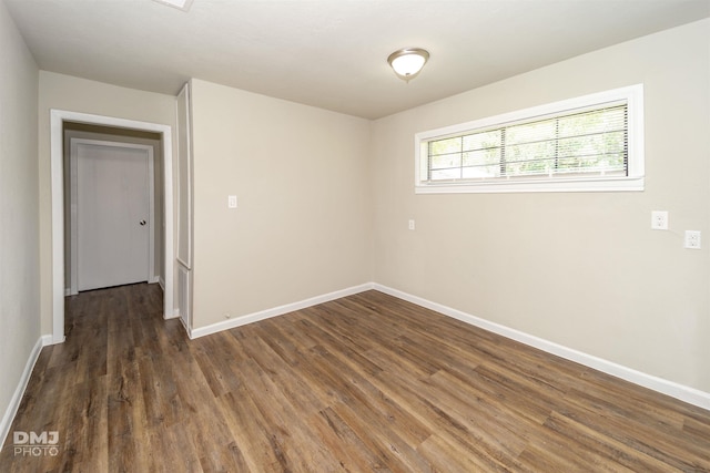 unfurnished room featuring baseboards and dark wood-type flooring