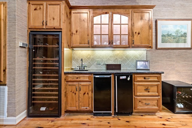 kitchen featuring light wood-type flooring, wine cooler, and dark stone counters