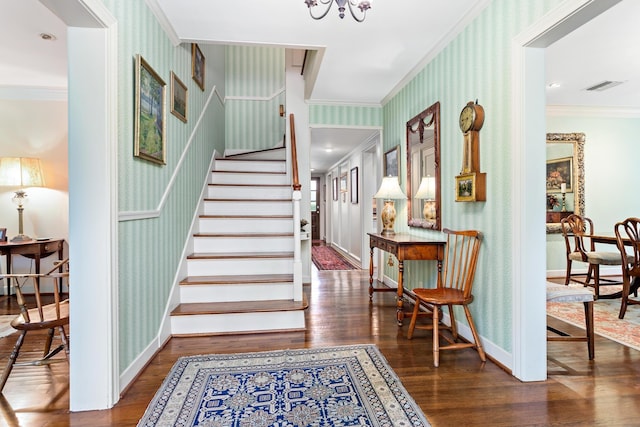 foyer entrance with an inviting chandelier, dark hardwood / wood-style floors, and ornamental molding