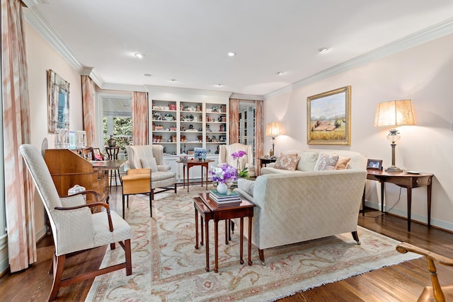 living room with built in shelves, wood-type flooring, and ornamental molding