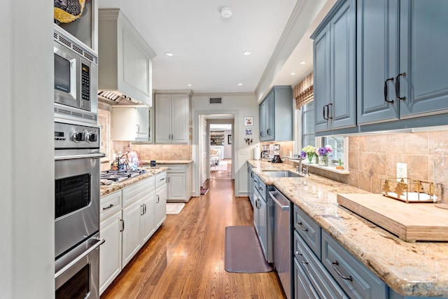 kitchen with sink, light hardwood / wood-style flooring, appliances with stainless steel finishes, tasteful backsplash, and white cabinetry