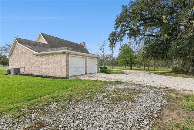 view of property exterior with a garage, central AC unit, and a lawn