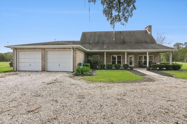 view of front of property with covered porch, a garage, and a front yard