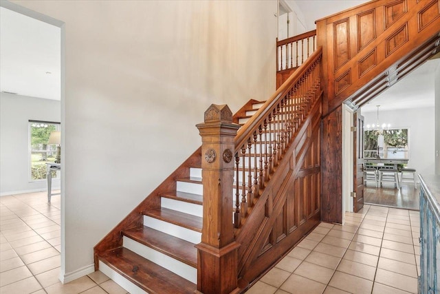 stairs featuring tile patterned flooring, a healthy amount of sunlight, and an inviting chandelier