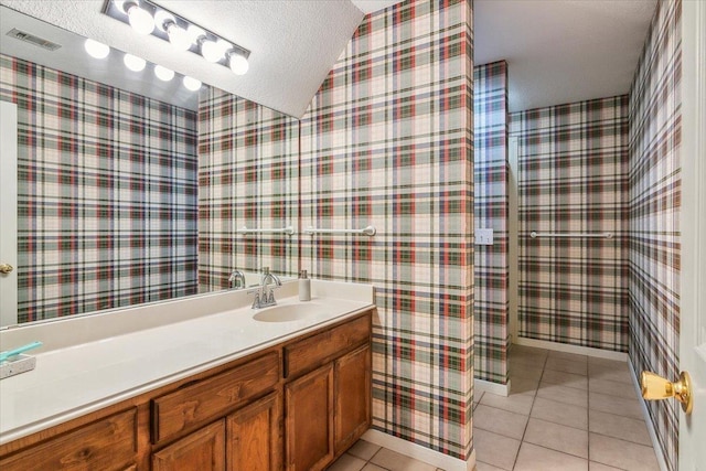 bathroom featuring a textured ceiling, tile patterned flooring, vanity, and vaulted ceiling