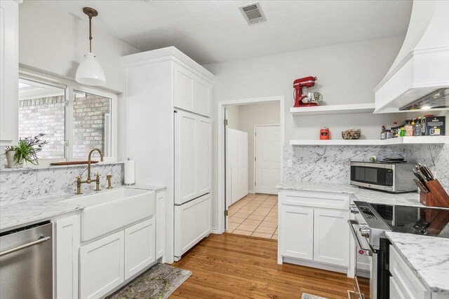 kitchen featuring white cabinets, appliances with stainless steel finishes, custom range hood, and sink