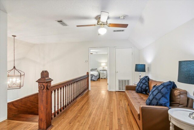 sitting room with ceiling fan with notable chandelier, lofted ceiling, and light hardwood / wood-style flooring