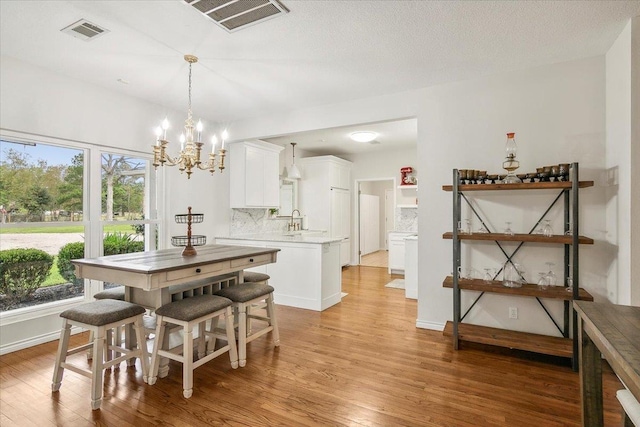 dining space with a chandelier, light hardwood / wood-style flooring, and sink