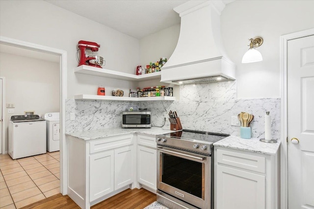 kitchen with backsplash, custom range hood, stainless steel appliances, washer and clothes dryer, and white cabinets