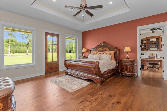 bedroom featuring hardwood / wood-style floors, ceiling fan, crown molding, and a tray ceiling