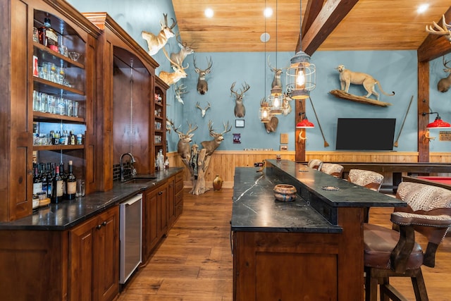 bar with pendant lighting, wood walls, sink, beam ceiling, and wood-type flooring