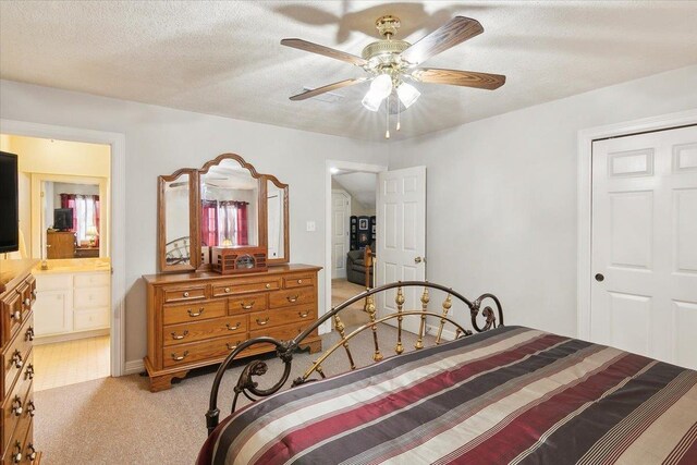 carpeted bedroom with ceiling fan, ensuite bathroom, and a textured ceiling