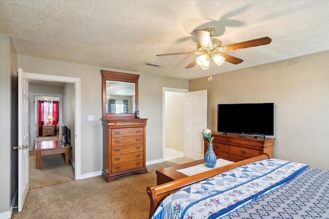 bedroom with ceiling fan, light colored carpet, and a textured ceiling