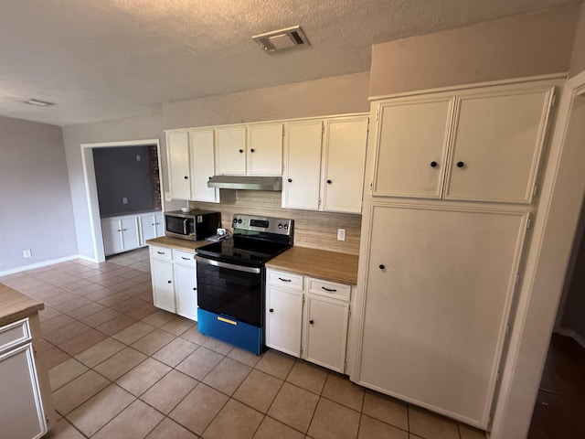 5085 Plant Rd, Beaumont, TX 77708 - kitchen featuring electric range, stainless steel microwave, under cabinet range hood, backsplash, and white cabinetry
