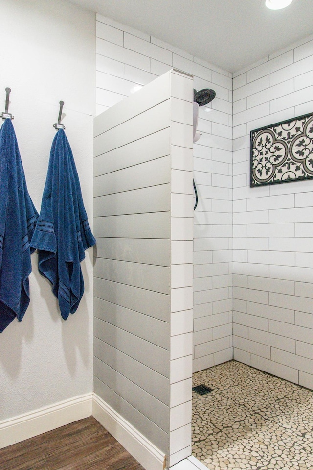 bathroom with tiled shower and wood-type flooring