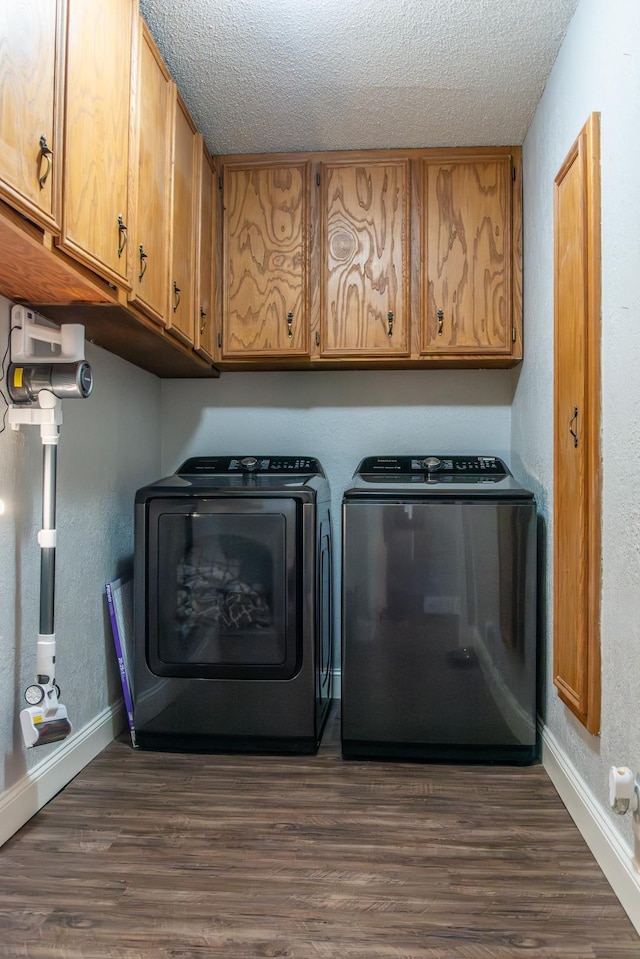 washroom featuring cabinets, dark hardwood / wood-style flooring, washer and dryer, and a textured ceiling