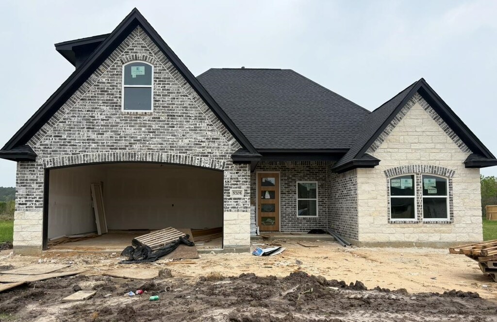 5705 Essie Ln, Beaumont, TX 77713 - french country inspired facade featuring stone siding, roof with shingles, an attached garage, and brick siding