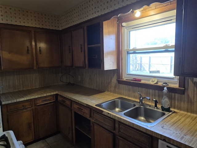 kitchen with sink, light tile patterned floors, and dark brown cabinetry