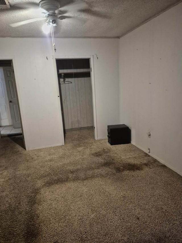 unfurnished bedroom with ceiling fan, carpet floors, and a textured ceiling