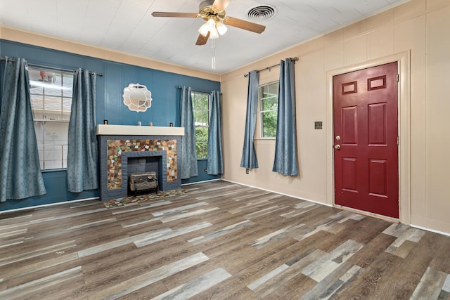 4300 Ferndale Dr, Port Arthur, TX 77642 - unfurnished living room featuring a ceiling fan, wood finished floors, a wood stove, a decorative wall, and ornamental molding