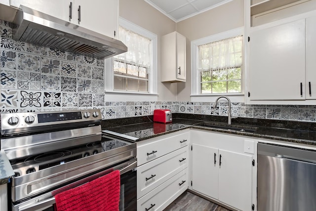 4300 Ferndale Dr, Port Arthur, TX 77642 - kitchen with appliances with stainless steel finishes, extractor fan, white cabinetry, backsplash, and crown molding