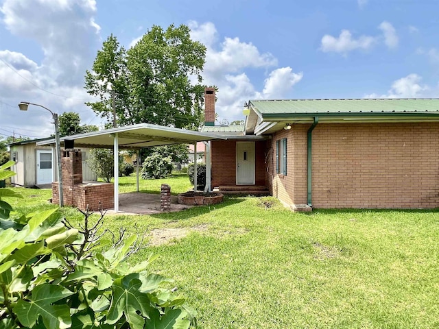 back of property featuring a lawn and a carport