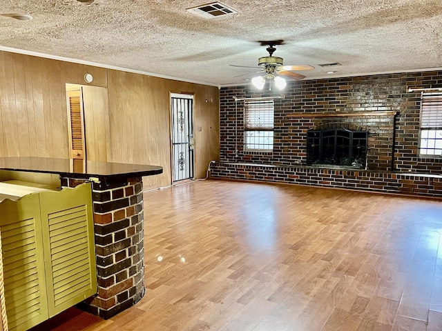 unfurnished living room with a wealth of natural light, wood walls, and brick wall