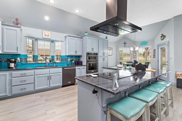 200 Skylark Ave, Bridge City, TX 77611 - kitchen with appliances with stainless steel finishes, island range hood, vaulted ceiling, light wood-type flooring, and a kitchen breakfast bar