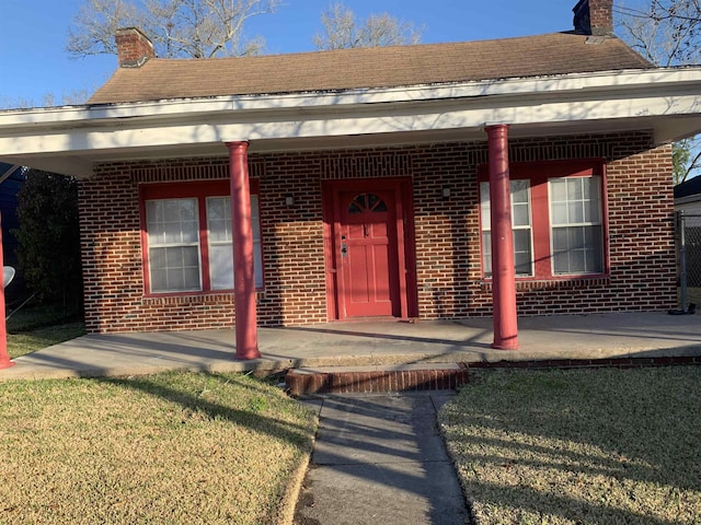 view of exterior entry with a porch and a yard